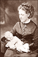 Foto av Isabel i halvfigur sittande med en baby i knät. Hon tittar ner mot babyn och den ser rakt in i kameran.
