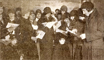 Foto av massor av kvinnor och några barn, varav många håller i en strejktidning. Alla har hattar och kappor på sig.