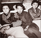 Foto av tre kvinnor (varav en är Durriya Shafiq) ligger i tjusiga pyamasar under hungerstrejken