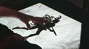 Lotte Reinigers händer som håller fast en siluett av Papageno på kamerabordet.