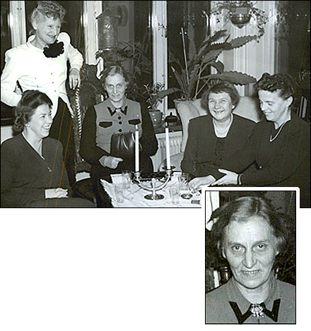 Foto av fem kvinnor på en middagsbjudning. De sitter finklädda i ett vardagsrum med stearinljus och glas på bordet. En uppförstoring av Märta Björnboms porträtt är unklippt i bilden