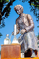 Foto av statyn föreställande Vera Sandberg sittande framför vätskefyllda flaskor