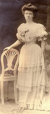 Foto av Louise de Bettignes i helfigur, stående med handen lutad mot en stol
