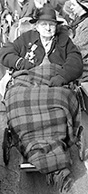 Foto av Helena Molony som äldre där hon halvligger utomhus med en filt över benen. Hon har hatt och glasögon och medaljer på jackan