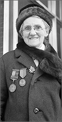 Foto av Rosie Hackett med kappa och mössa, hon har flera medaljer på kappan och ler mot kameran