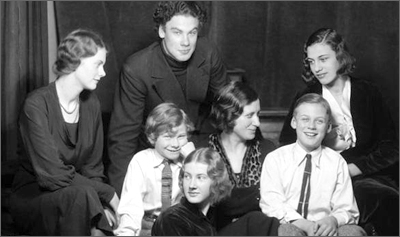 Foto av Célie Brunius omgiven av sina sex barn. De ser glada ut, skrattar eller ler och swer på varandra eller in i kameran