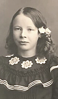 Foto av Ester Blenda som barn i klänning med volang och rosetter i håret
