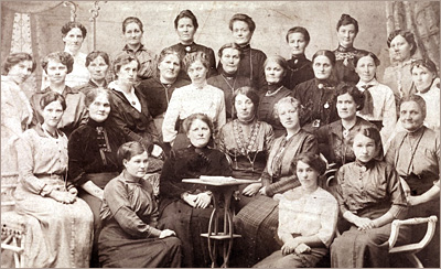 Foto av en grupp kvinnor, sittande och stående. Av kläderna framgår att de inte är fina damer, och att det är runt sekelskiftet 1800-1900-tal