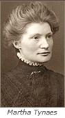 Porträttfoto av kvinna från sekelskiftet 1900. Hon har håret uppsatt och tittar snett åt höger. Under bilden står: Martha Tynaes