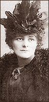 Foto av ung Maud Gonne iförd en tjusig hatt. Vid halsen har hon Inghinide na hÉireanns typiska Tarabrosch.