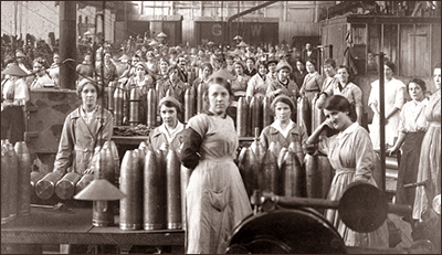 Foto av massor av kvinnor i en fabrik. De har skyddskläder och det står bomber överallt.