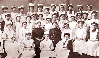 Foto av 33 kvinnor varav alla utom två är iförda ljusa dräkter. De sitter respektive står i fyra rader.