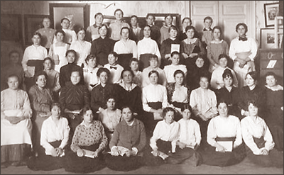 Foto av kvinnor som sitter och står i flera rader, de längst fram sitter på golvet.