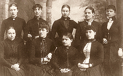 Foto av nio kvinnor (fyra sittande och fem stående) som var medlemmar i Stockholms allmänna kvinnoklubb