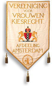 Foto av banderoll i orange och rött med tre tofsar nedtill. På den står: Vereeniging voor Vrouwenkiesrecht och sedan: Afdeeling Amsterdam