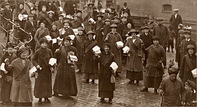 Foto av massor av kvinnor som står med flygblad i händerna ute på en gata