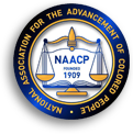 RocKmärke med en ytterrand av gul text på blå botten: "National Association for the Adnacement of Colored People" och i mitten en vågskål och texten NAACP 1909