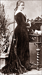 Foto av Rosa i helfigur som ung. Hon har en lång mörk klänning och håret i en fläta som går ända ner till stjärten