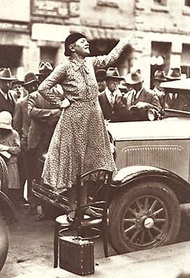 Foto av Adela Pankhurst stående på en stol på gatan och hållandes tal
