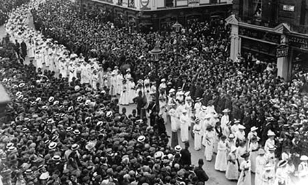 Begravningståget med vitklädda suffragetter i kontrast till de mörkare åskådarna på bägge sidor, foto taget snett uppifrån