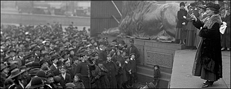 Emmeline Pankhurst står till höger ovanför folkmassor till vänster i bild
