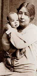 Foto i halvfigur av Sylvia med sin son som baby i famnen