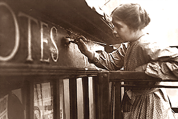 Foto av Sylvia Pankhurst som målar en text om rösträtt på en vägg ovanför ett fönster
