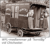 Foto av en vagn som det står Women's Freedom League på och två kvinnor står en ena änden. Under bilden står: WFL-medlemmar på "korståg"# vid Chichester
