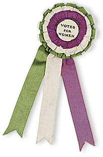 Rockmärke med band i suffragetternas färger grönt, vitt och lila och i mitten står: Votes for Women