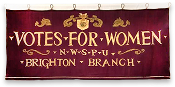 Foto av broderad banderoll med texten: Votes for Women - NWSPU - Brighton Nranch