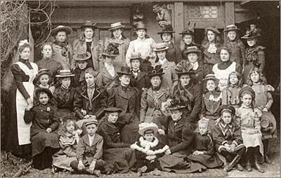 Foto av vuxna kvinnor och flickor som sitter och står utomhus. De har hattar och kappor på sig
