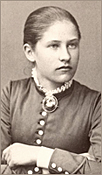 Foto av Lydia som 15-åring 1884. Hon har håret strikt till huvudet, ser åt sidan och har en kamébrosch på blusen