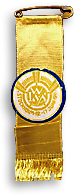 Foto av kongressmärket med en rostig säkerhetsnål. Det är ett gult sidenband med frans nedtill och rösträttsden runda symbolen i mitten