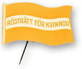 Rockmärke med nål, en gul flagga med vit vågrätt rand i mitten, där det står "Rösträtt för kvinnor"