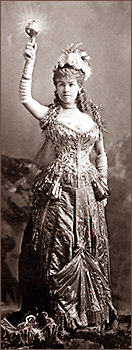 Foto av kvinna i den berömda Electric Light-klänningen. Hon håller upp ena armen, som hon har facklan i.