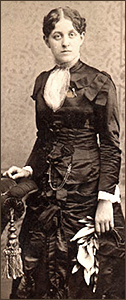 Foto av Carrie som ung i helfigur. Hon håller ena handen mot en fåtölj, i den andra har hon en sjal och hon ser rakt in i kameran