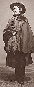 Foto av Elizabeth Smith Miller i helfigur iklädd byxor, kjol, jacka och hatt