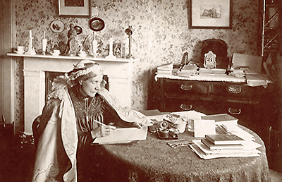 Foto av Josephine Butler på äldre dar där hon sitter i hemmet vid ett bord och skriver