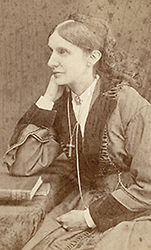 Foto av Josephine Butler i halvfigor, sittande framför ett bors med en bok, hon ser åt sidan