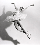 Balettdansös i luften med skugga på väggen till vänster
