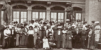 Foto av massor av kvinnor utanför en byggnad med två stora statyer av män