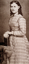Nästan helfigurfoto av Alma Åkermark som 18-åring, en typisk fotografbild, där hon står och håller sig i en stol