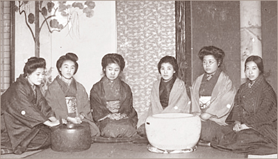 Sex japanska kvinnor i kimono sitter på golvet runt störa skålar