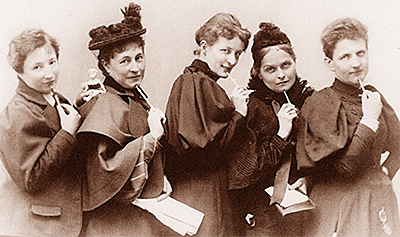Foto av fem kvinnor på rad, där alla har en penna i handen och håller den mot hakan eller munnen
