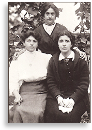Foto av tre kvinnor, två sitter och en står bakom dem med händerna vilande på deras axlar.