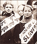 Foto av två småtjejer i halvfigur. De har banderioller på sig, på den enda står det Abolish Slavery, på den andra verkar det stå något på jiddish. De ser rakt in i kameran.