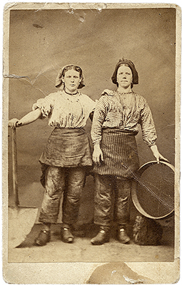 Foto av två tjejer i byxor, en med spade och en med en sorts sil