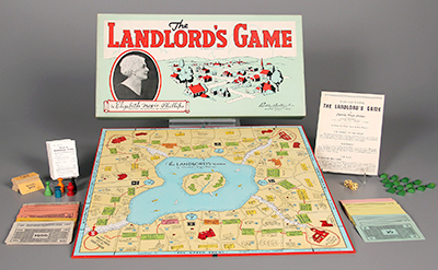 Foto av spelet "The Landlord's Game", med kartong, spelplan, pjäser, spelregler och diverse annat. Ett porträtt av Elizabeth Magie finns på kartongen