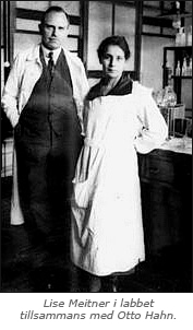 Foto av en man och en kvinna i ett laboratorium. Under bilden står texten: Lise Meitner i labbet tillsammans med Otto Hahn