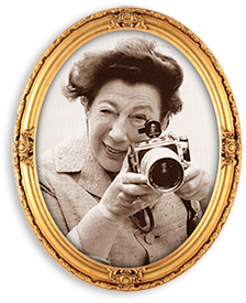 Porträttfoto i guldram av Anna Riwkin med kameran framför sig, beredd att fotografera.
